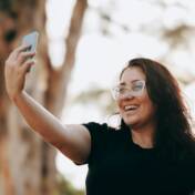 Hymyilevä nainen ottaa selfietä.
